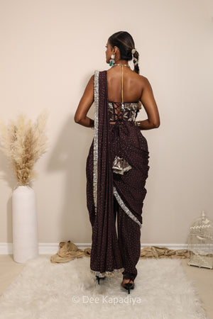 Woman in a floral brown and gold/silver patterns traditional dhoti saree outfit with jewelry, standing against a plain background. Ahilya corset top with Devi Dhoti saree back in espresso plum chocolate plum for wedding, bridal haldi, mehendi jaggo, sangeet indian wedding events 