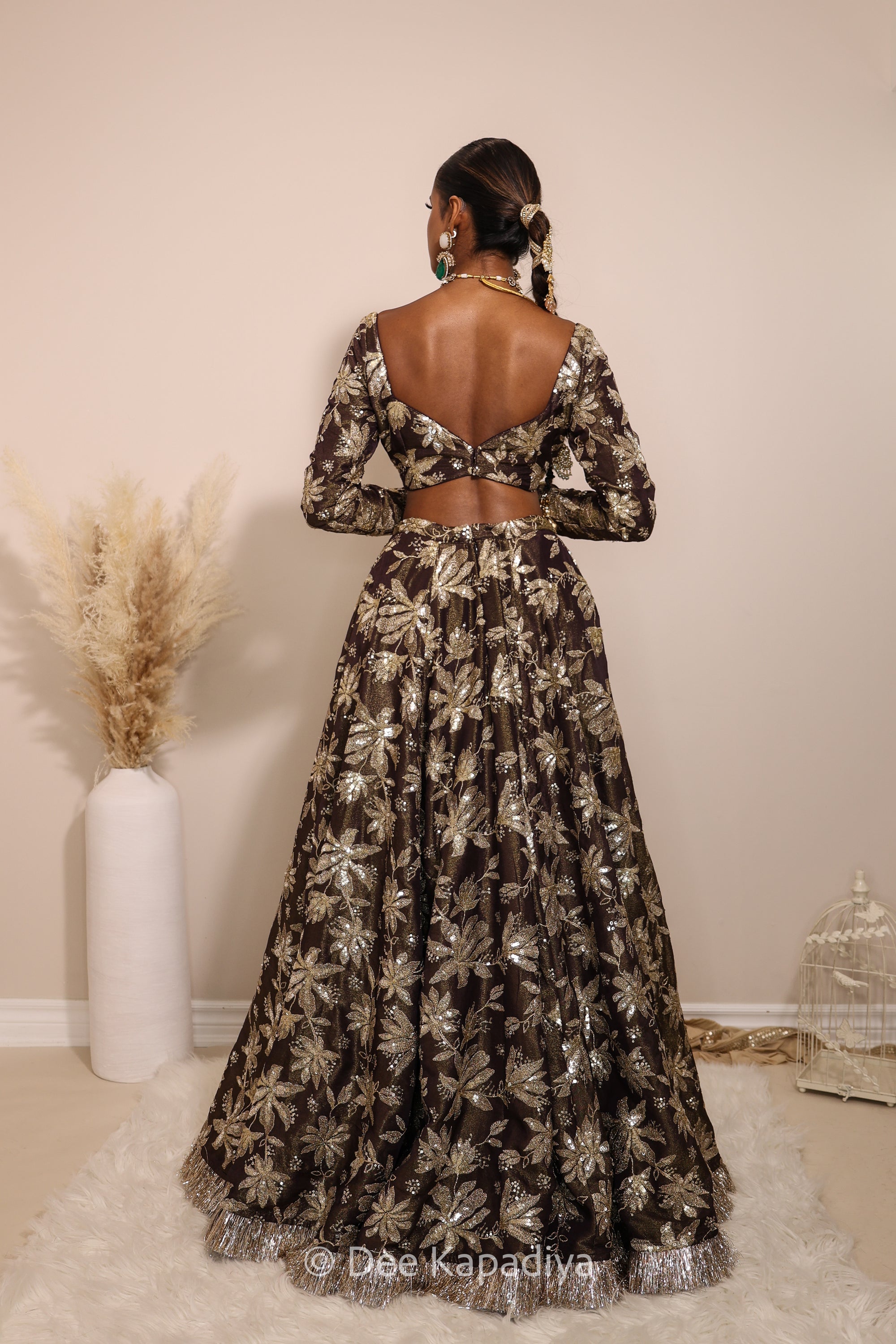 Woman in a floral lehenga skirt with a sheer dupatta standing against a neutral background. Lakshmi top with Jodha Lehenga back in espresso plum chocolate brown for haldi, mehendi jaggo, sangeet indian pre-wedding events