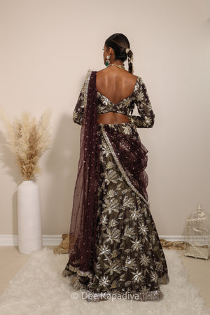 Woman in a floral mermaid lehenga skirt with a sheer dupatta standing against a neutral background. Lakshmi top with Vaani Lehenga back in espresso plum chocolate brown for wedding, bridal haldi, mehendi jaggo, sangeet indian wedding events