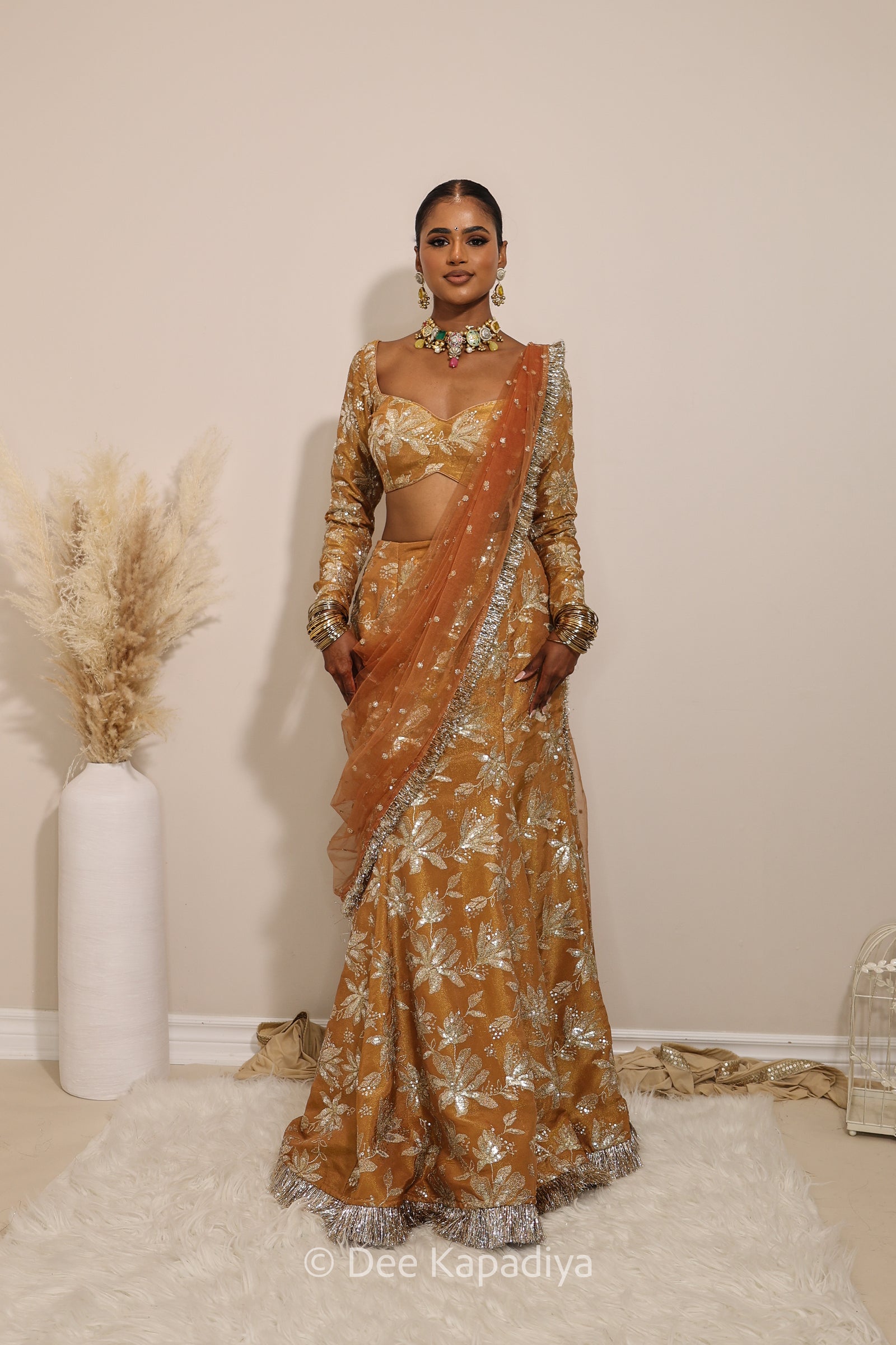 Woman in a floral yellow and gold/silver patterns traditional mermaid lehenga outfit with jewelry, with a sheer dupatta standing against a plain background. Lakshmi top with Vaani marmaid Lehenga front in espresso plum chocolate brown for wedding, bridal haldi, mehendi jaggo, sangeet indian wedding events 