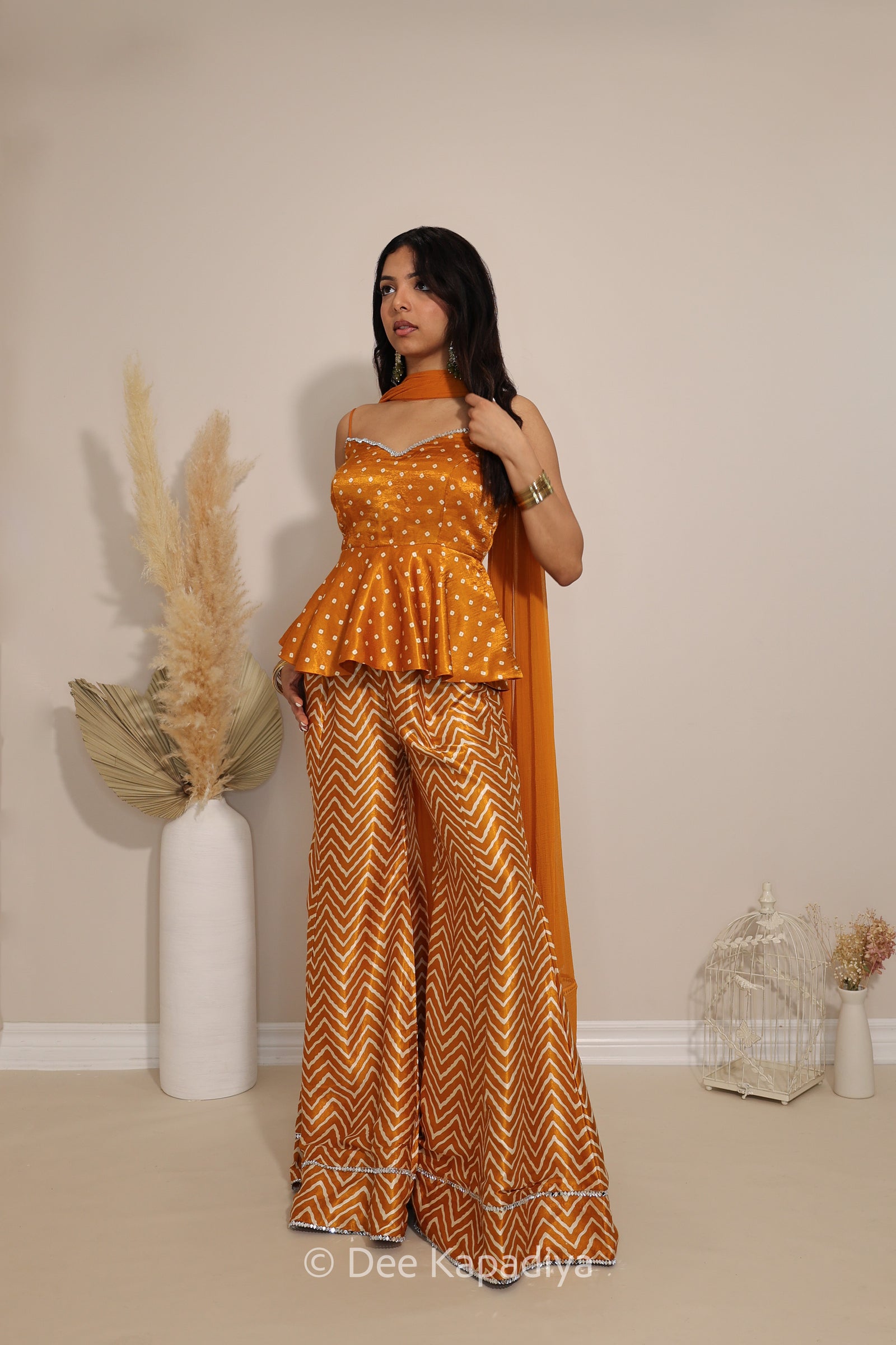 Model wearing Dee Kapadiya Nakhra Gharara Set in Haldi with mirror-work peplum top, chevron pants and chiffon dupatta