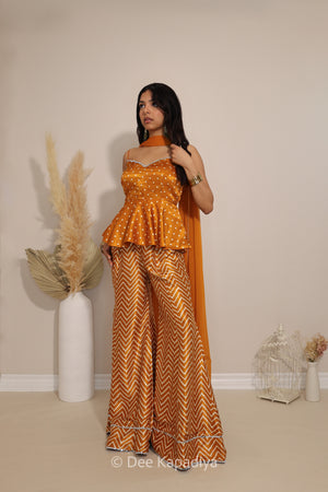 Three-quarter view of Dee Kapadiya Nakhra Gharara Set in Haldi with mirror-work peplum top and chiffon dupatta