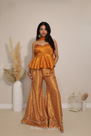 Model wearing Dee Kapadiya Nakhra Gharara Set in Haldi with mirror-work peplum top, chevron pants and chiffon dupatta