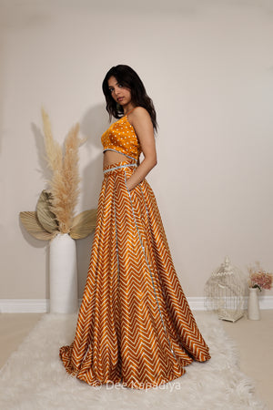 Side view of Dee Kapadiya Tamasha Lehenga Set in Haldi showing the one-shoulder bandhani print Pataka crop top, chevron lehenga and chiffon dupatta