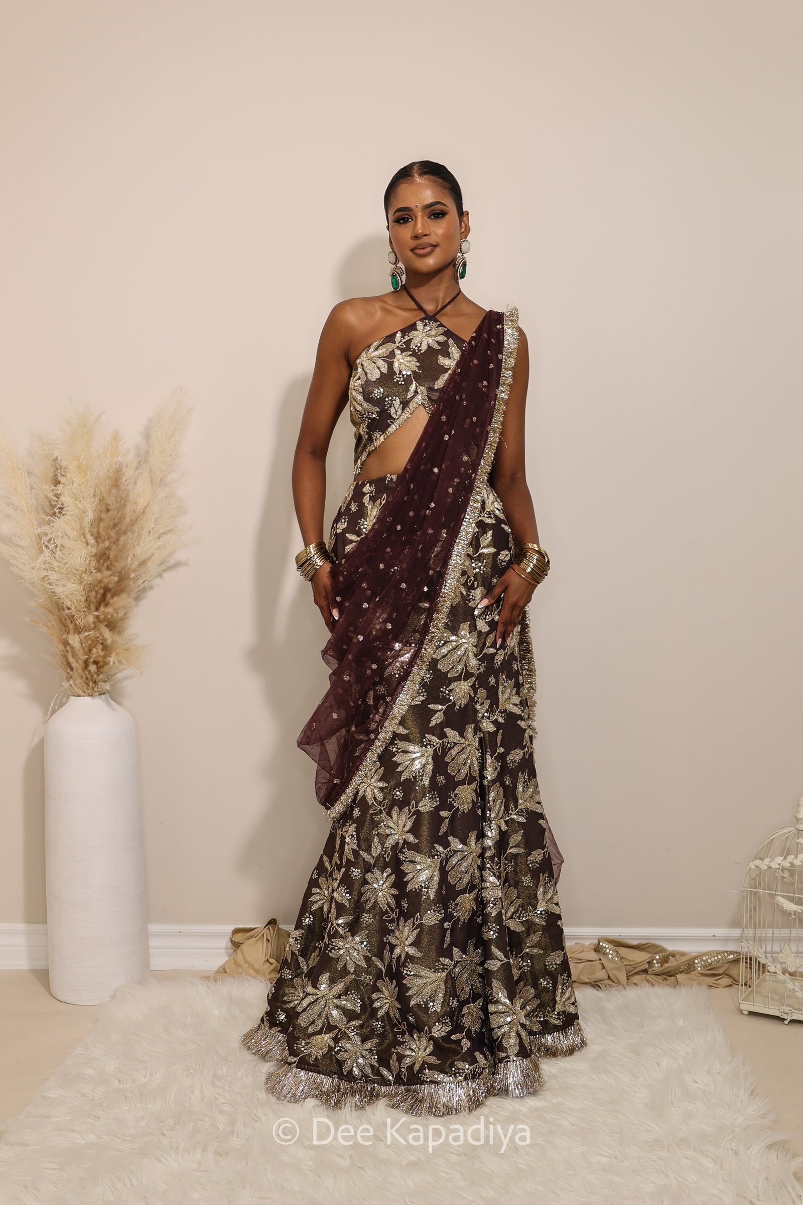 Woman in a floral brown and gold/silver patterns traditional mermaid lehenga outfit with jewelry, with a sheer dupatta standing against a plain background. Vaani top with Vaani marmaid Lehenga front in espresso plum chocolate brown for wedding, bridal haldi, mehendi jaggo, sangeet indian wedding events 